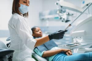 Dentist with drill treats caries to female patient, visit in dental clinic. Woman in dentistry cabinet, stomatology