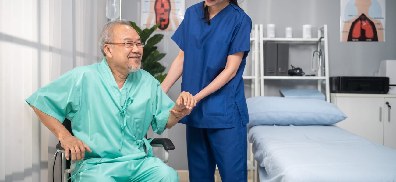 Asian young woman therapist support senior old man patient at hospital. Attractive female specialist doctor doing physical therapy procedure for elderly mature male for health care during appointment.